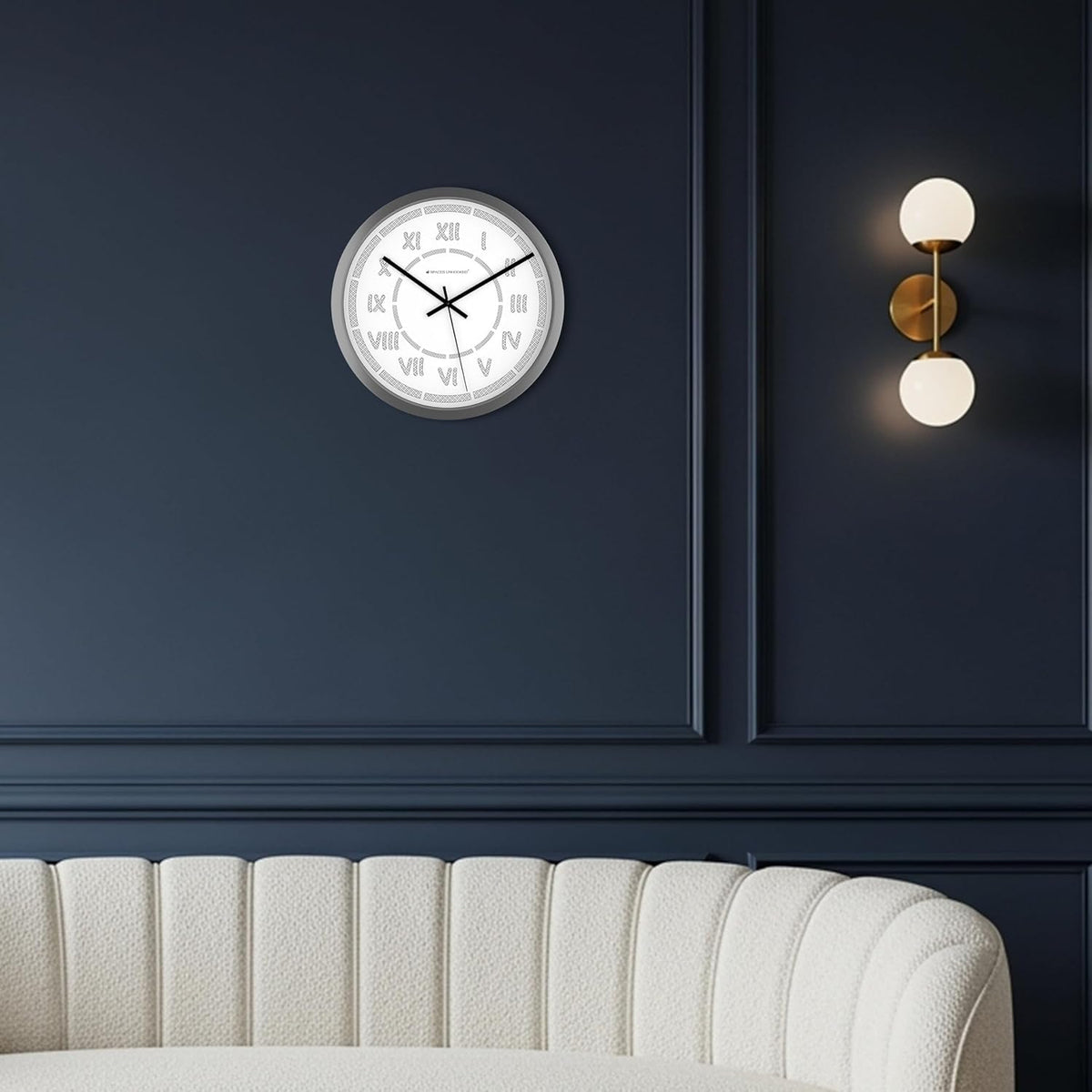 Wall clock on a dark blue wall with a light fixture and white sofa in the foreground
