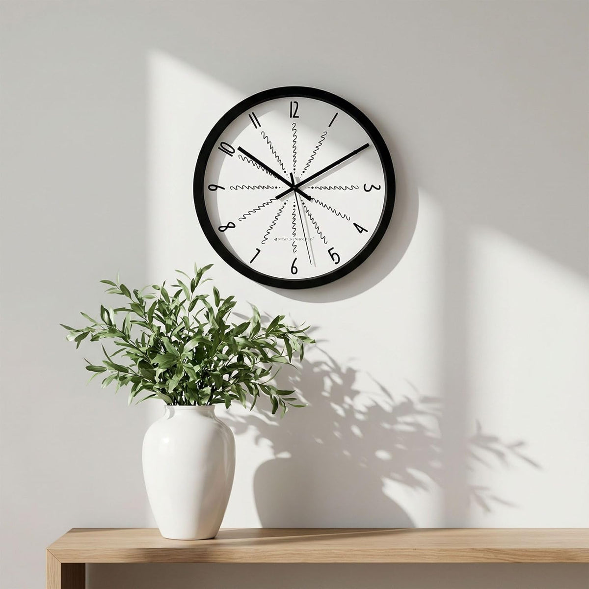 Wall clock with a plant on a wooden shelf against a light wall