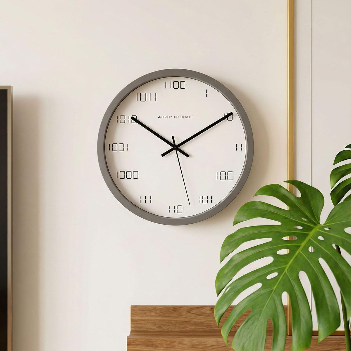 Wall clock on a white wall with a plant in the foreground