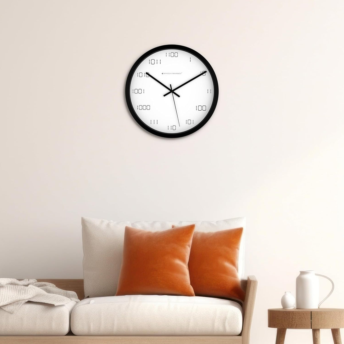 Wall clock on a wall above a sofa with orange cushions