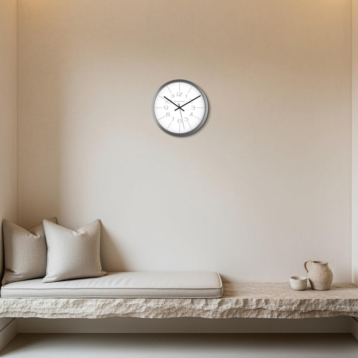 Wall clock on a beige wall above a cushioned bench with pillows.