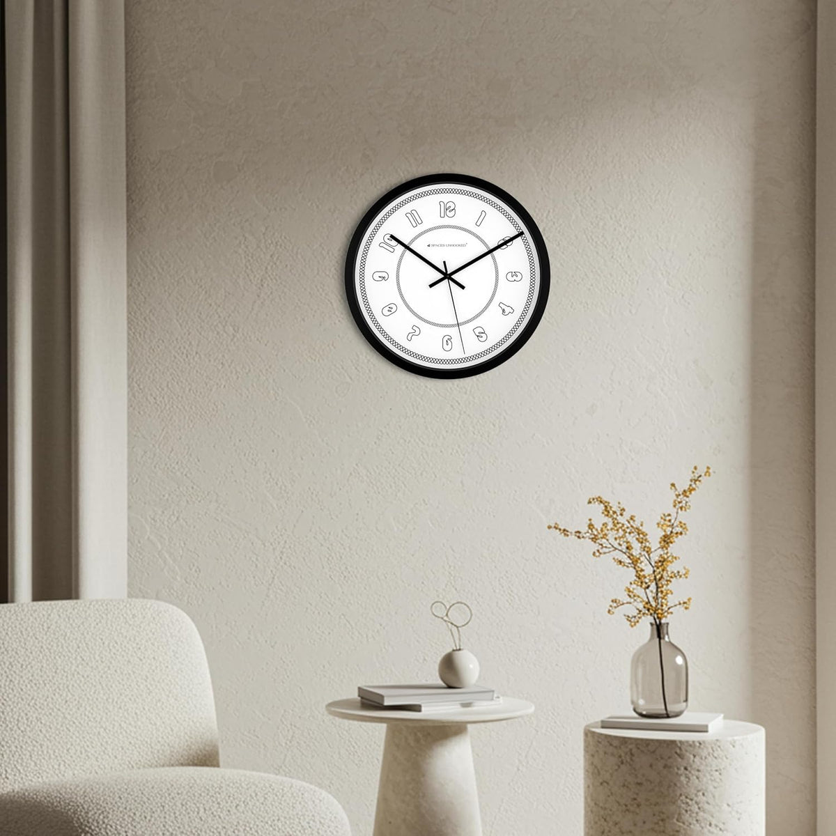 Wall clock on a neutral wall with a chair and small table in the foreground