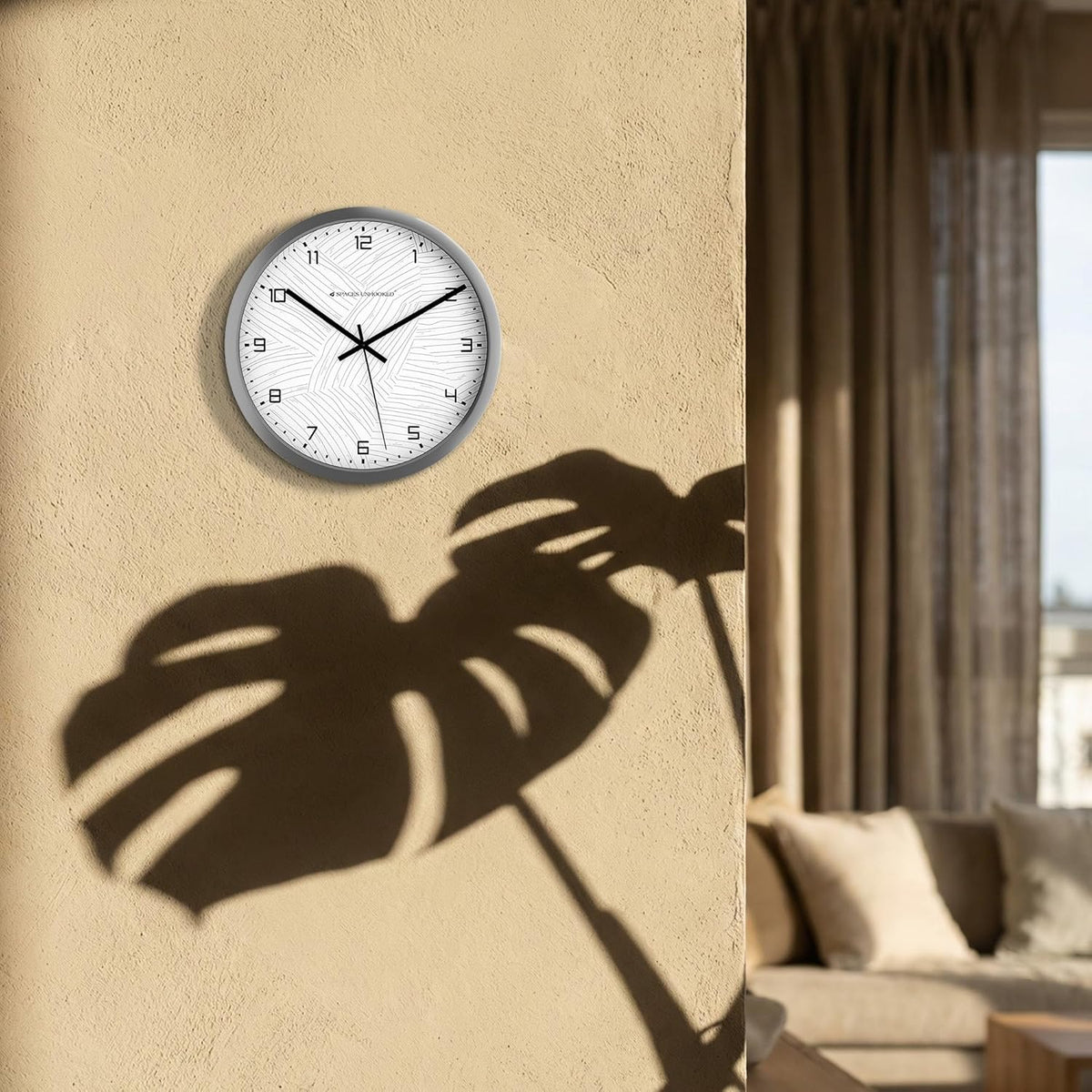 Wall clock on a beige wall with a leaf shadow, living room setting