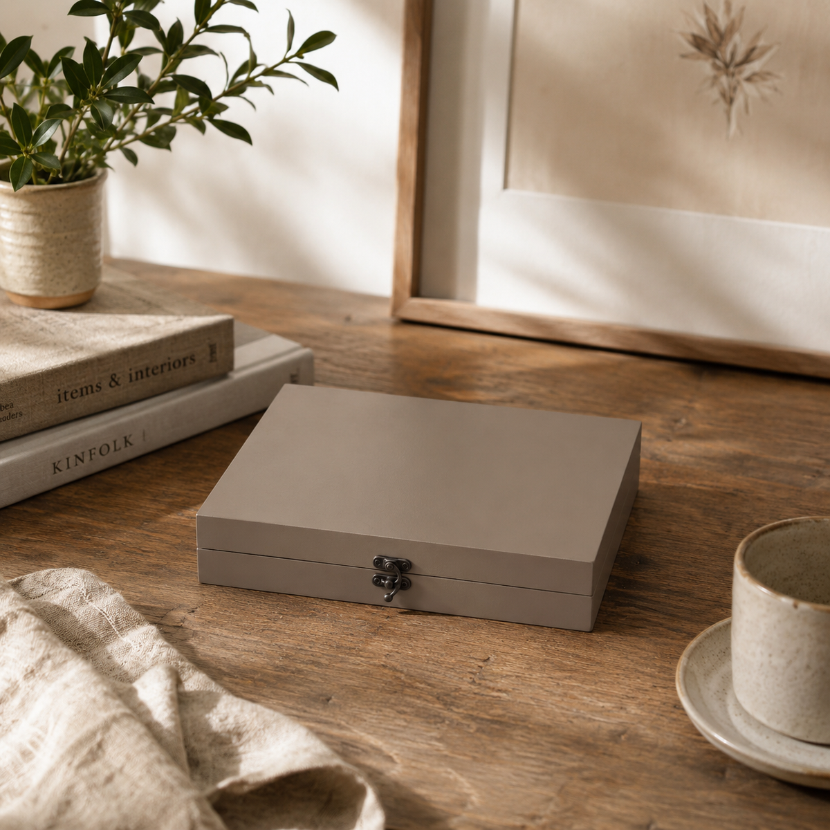 Gray wooden box on a wooden surface with a plant and books in the background