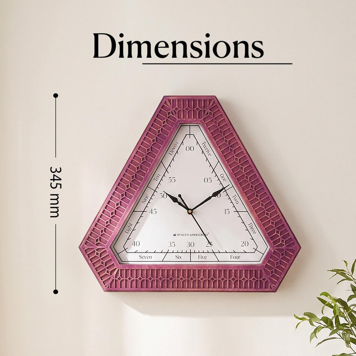 Triangular magenta wall clock on a creative studio wall above a desk