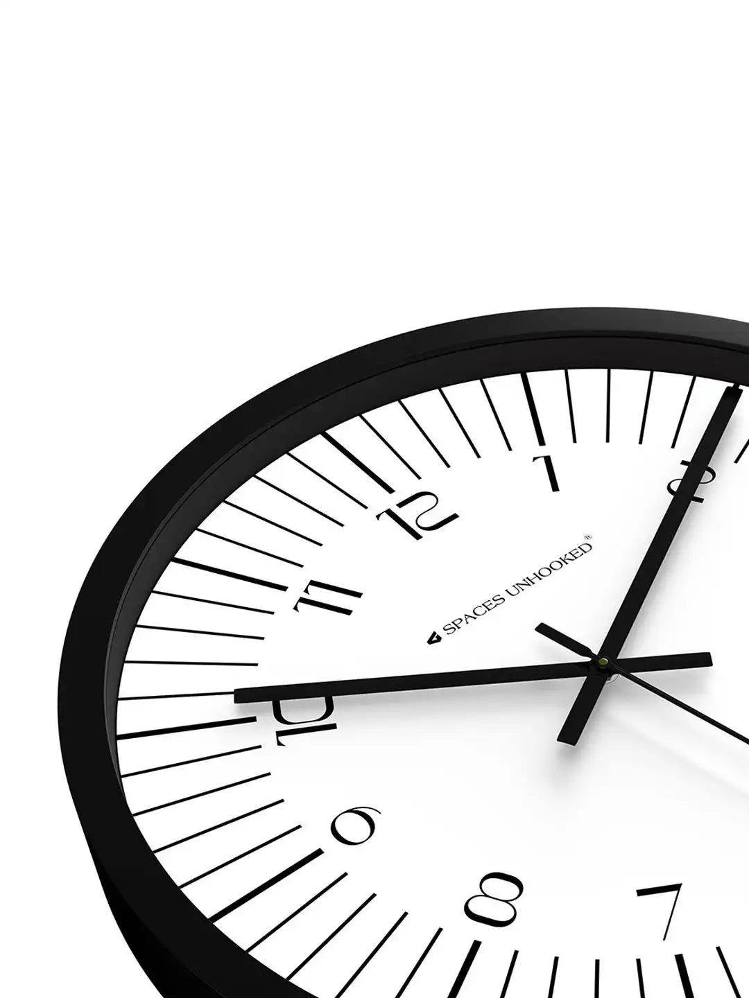 Close-up angled front view of Spaces Unhooked black wall clock with white dial and minimalist Arabic numerals