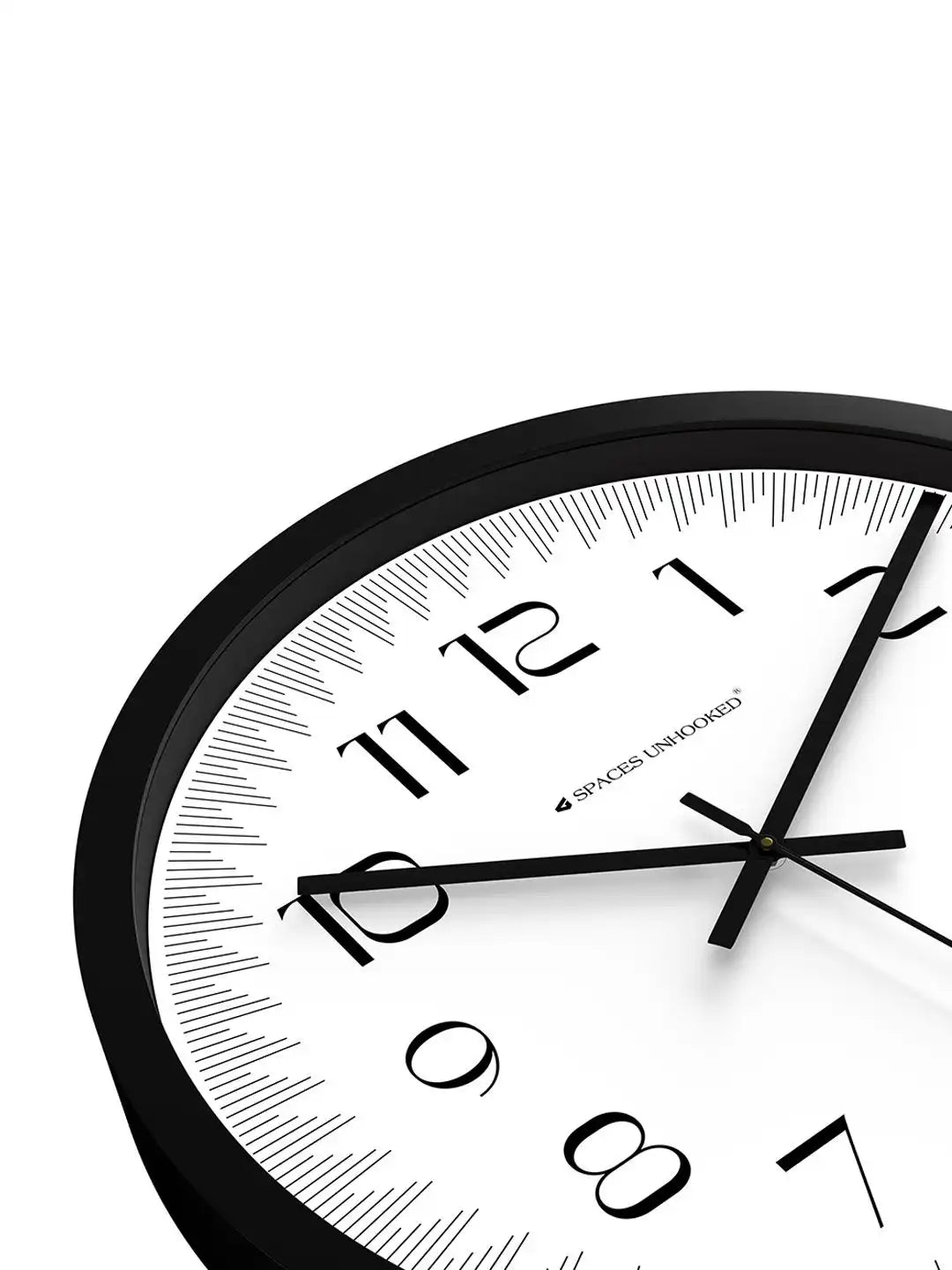 Close-up angled front view of Spaces Unhooked black wall clock with white dial and Arabic numerals