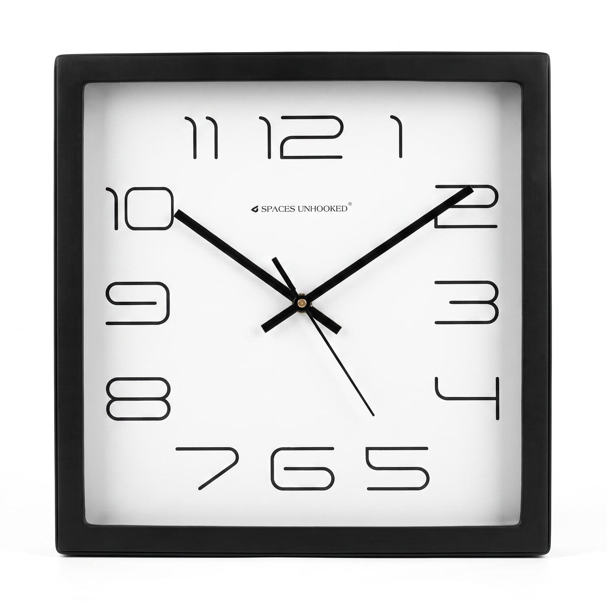 Square black and white wall clock on a plain wall in a tidy home office