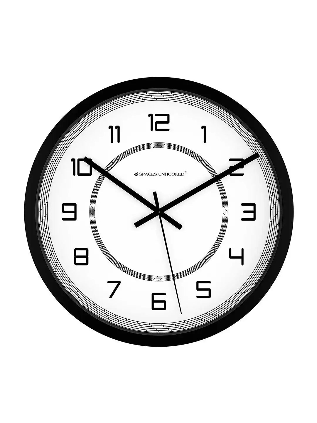 Front-facing view of black-framed wall clock with white dial, Arabic numerals, and Spaces Unhooked branding