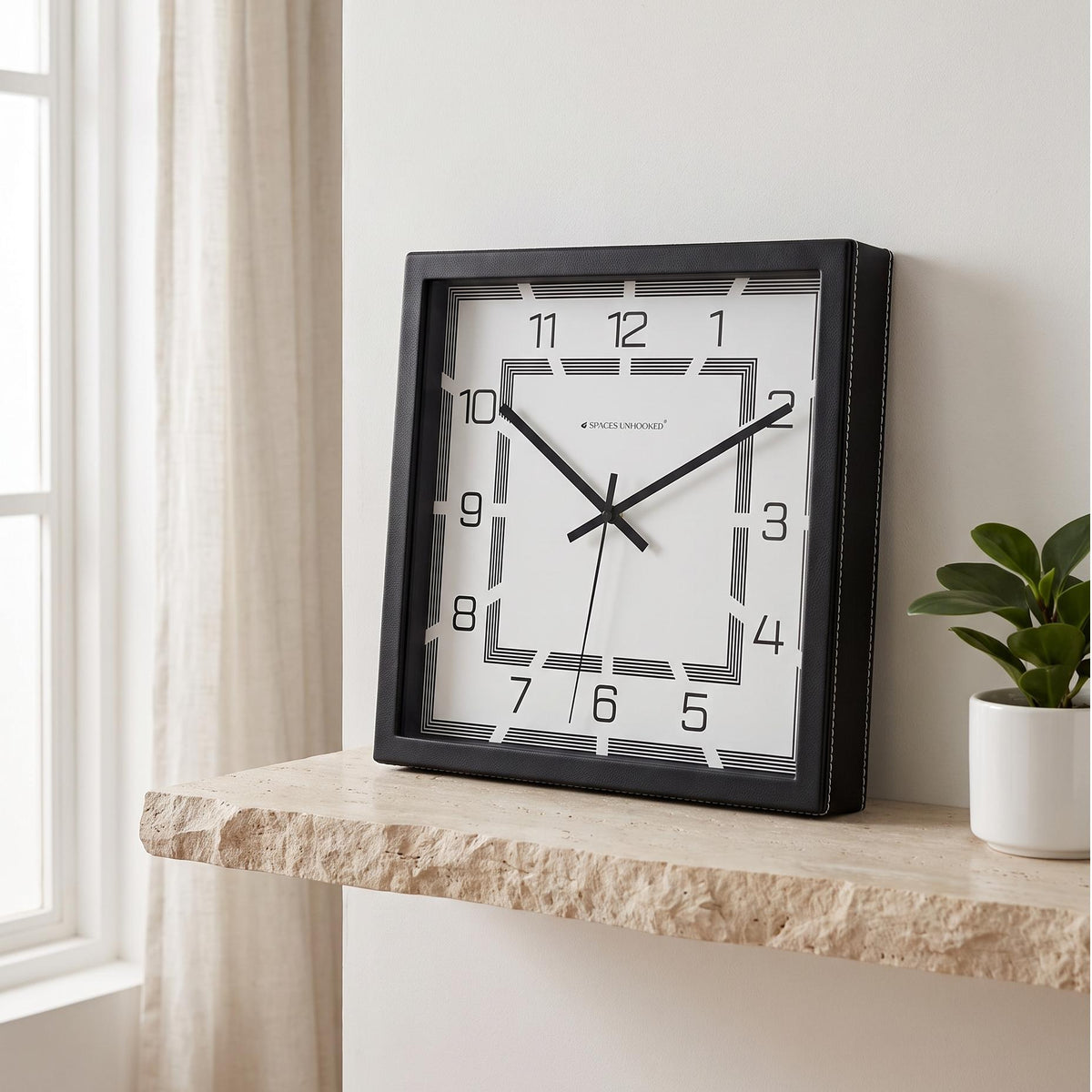 Black square art deco wall clock in a home office above a work desk