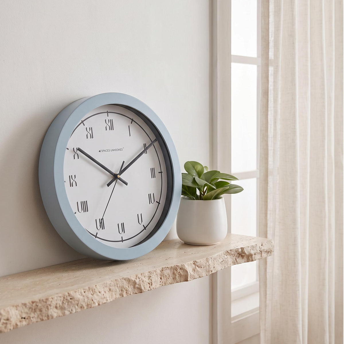 Spaces Unhooked powder blue round wall clock with Roman numerals on a white dial, front view