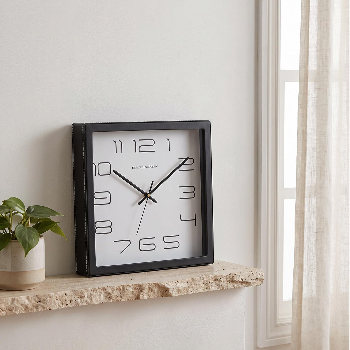 Square black wall clock with slim outlined numerals on a white dial, front view