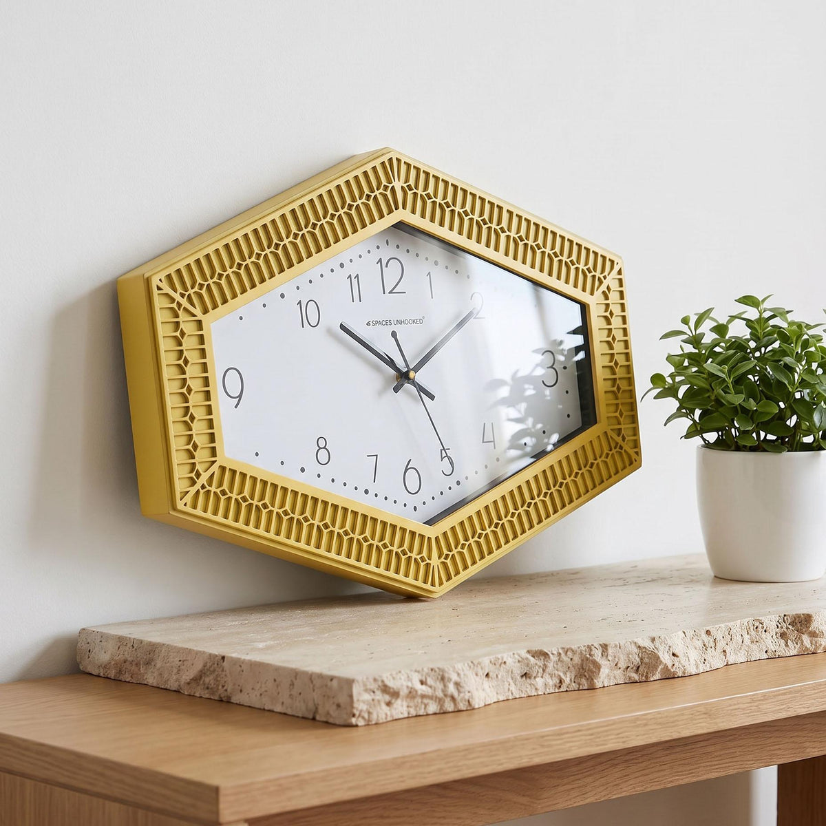 Elongated hexagonal wall clock with yellow carved frame and dotted dial on white