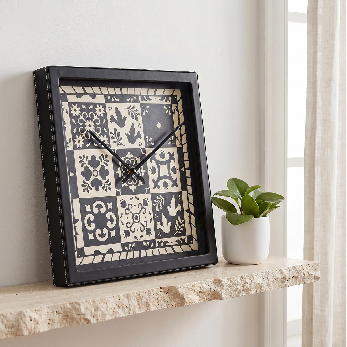 Square black wall clock with black and cream folk art tile dial, front view