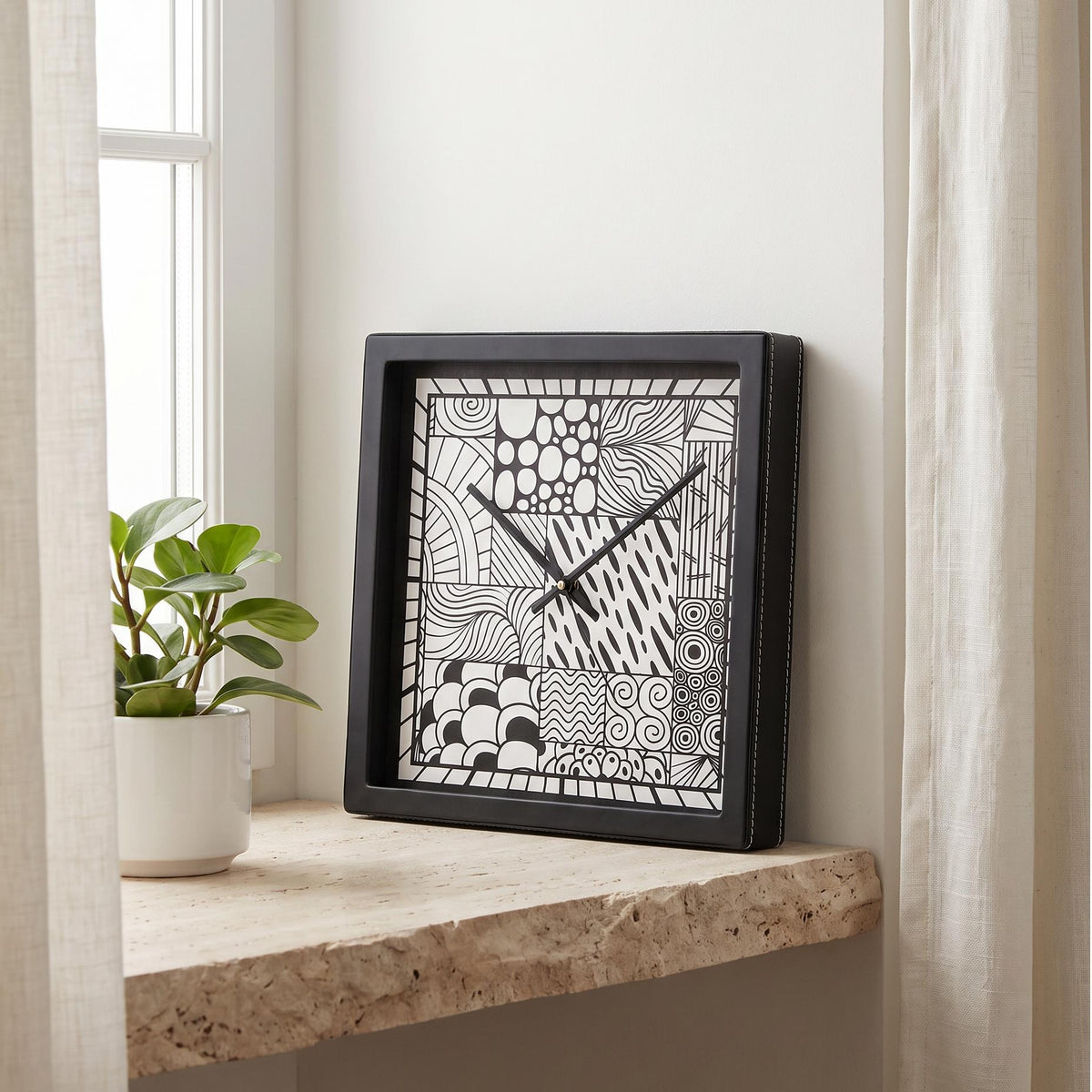 Square black wall clock with black and white doodle art patchwork dial, front view