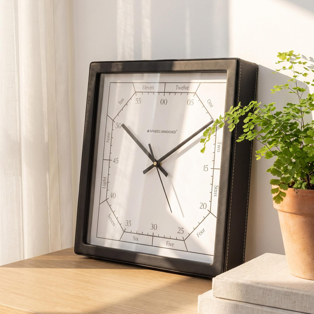Square black wall clock with hours spelled in words and minutes in fives, front view