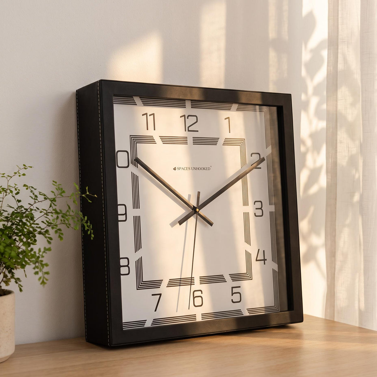 Slim black hands and thin second hand over nested striped squares on the dial