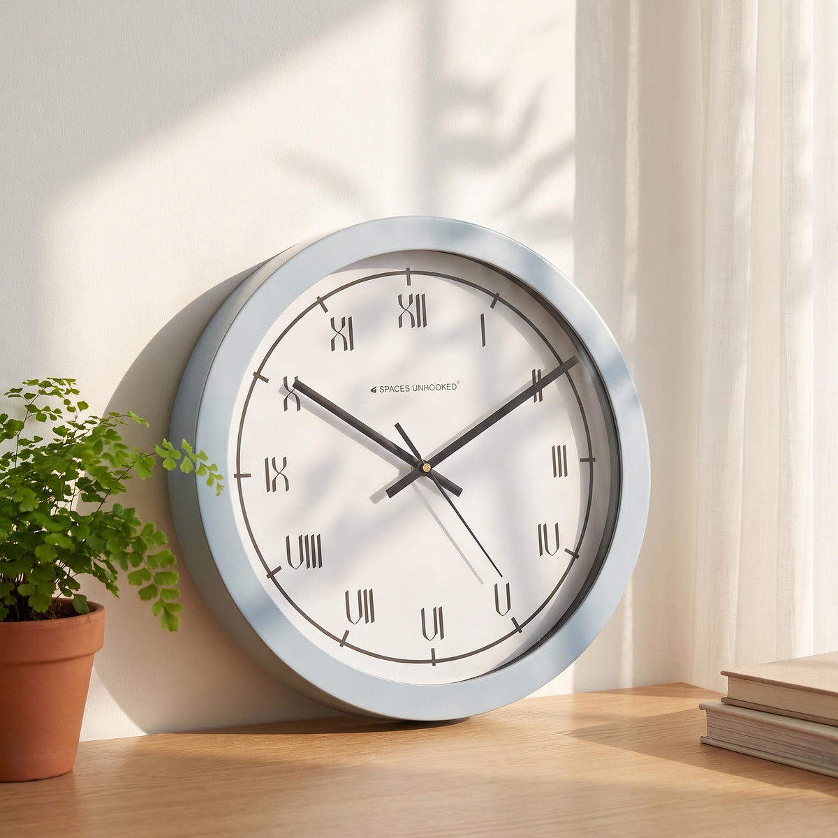 Black hands and thin second hand over the white Roman numeral dial of a blue wall clock