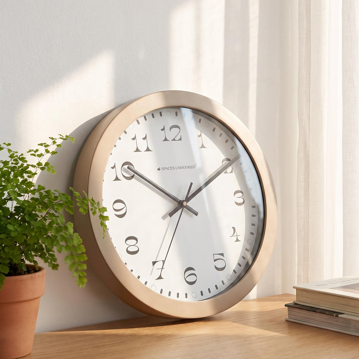 Black hands and thin second hand over the serif numeral dial of a taupe wall clock