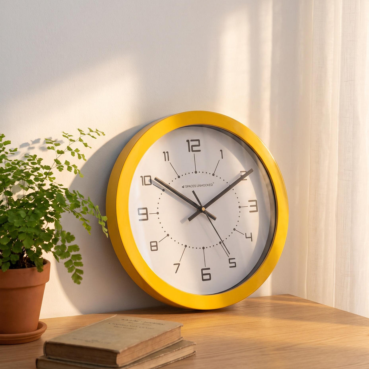 Black hands and thin second hand over the open white centre of a yellow wall clock