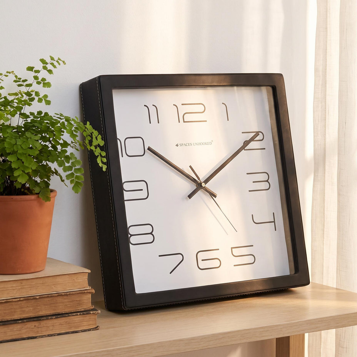 Minimal black wall clock on a kitchen wall beside open shelves