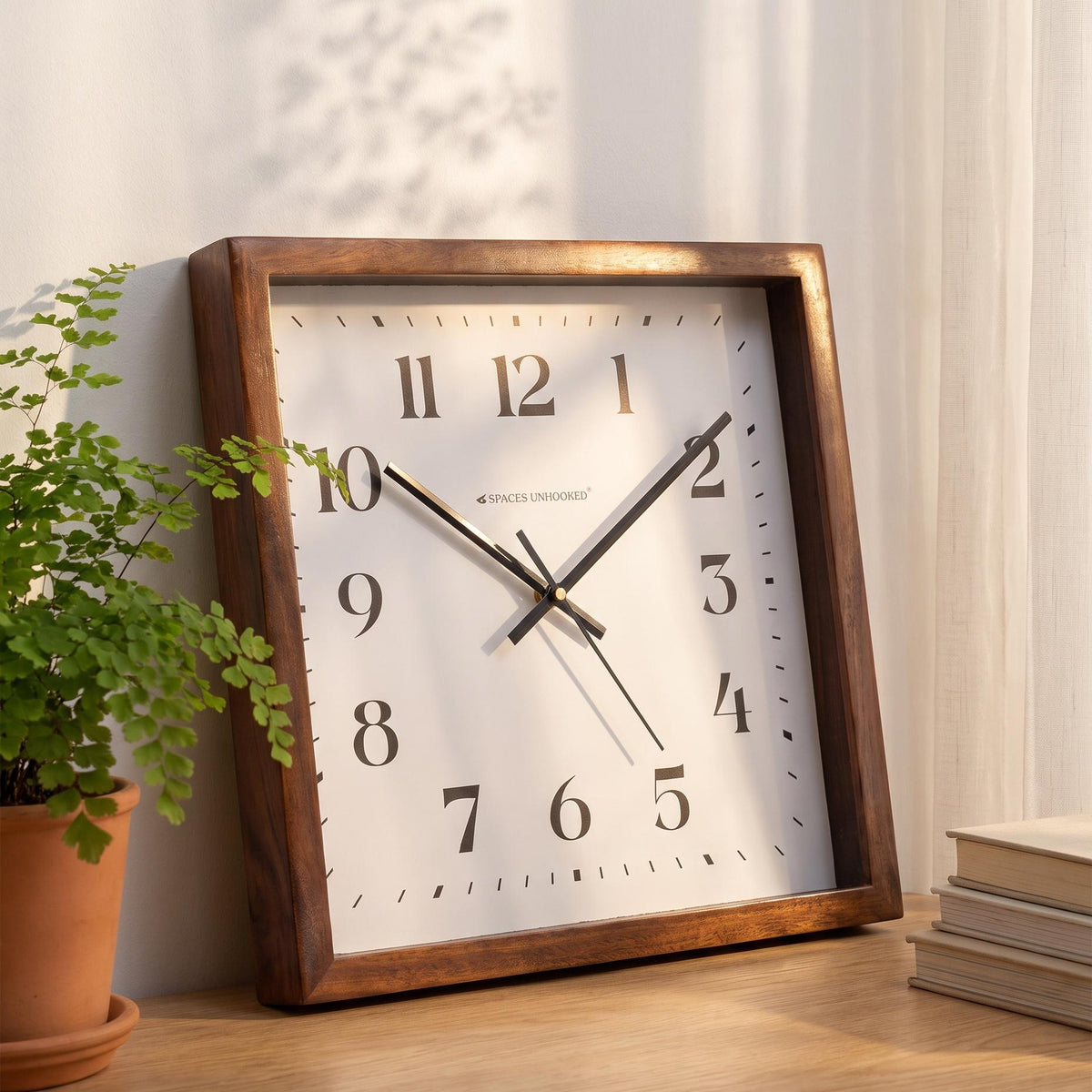 Square wooden wall clock with black numerals styled above a console table in a hallway