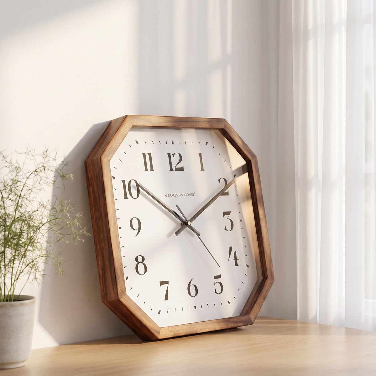 Octagonal wooden wall clock with black numerals above a console table in a welcoming hallway