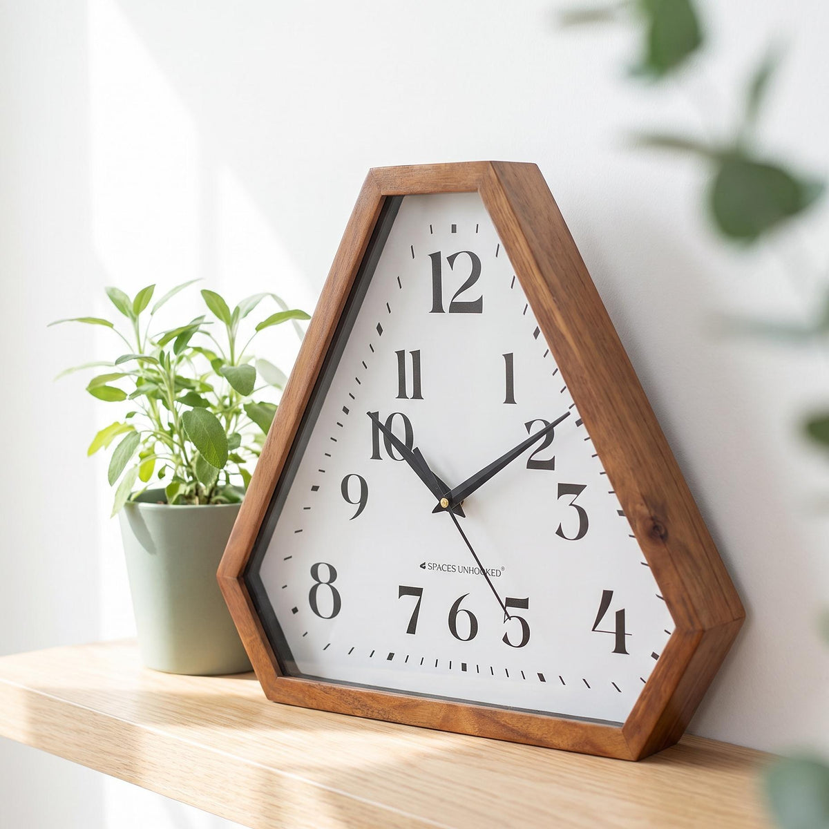 Spaces Unhooked triangular wooden wall clock with bold black numerals on a white dial, front view