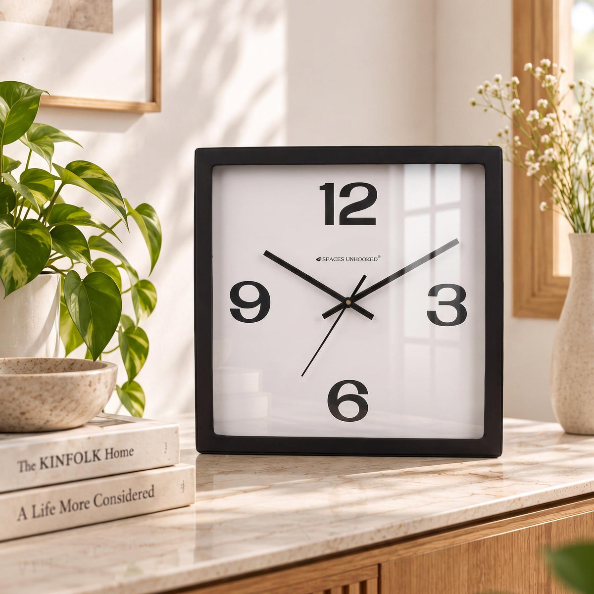 Bold 12-3-6-9 wall clock on a kitchen wall beside open shelves
