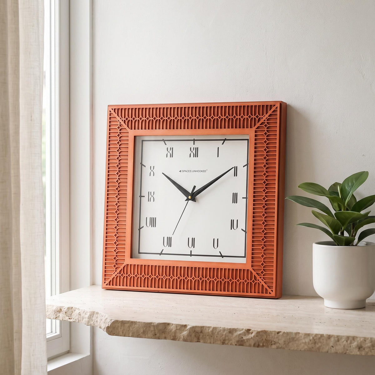 Square wall clock with terracotta arch-pattern frame and Roman numerals on white dial