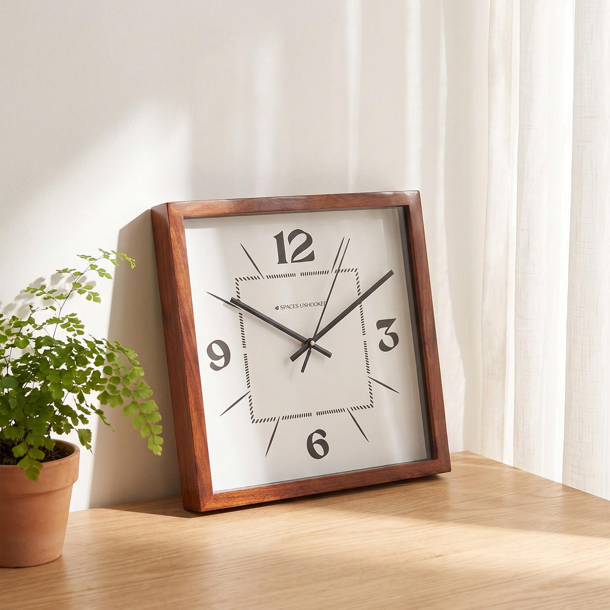 Dotted dial square wooden wall clock in a gallery wall arrangement with black-framed prints