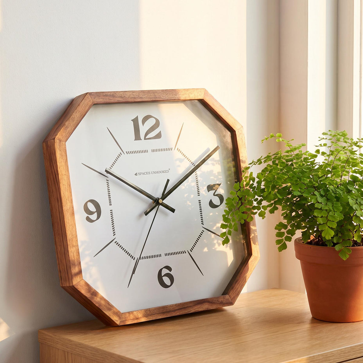 Dotted dial octagonal wooden wall clock in a gallery wall arrangement with black-framed prints