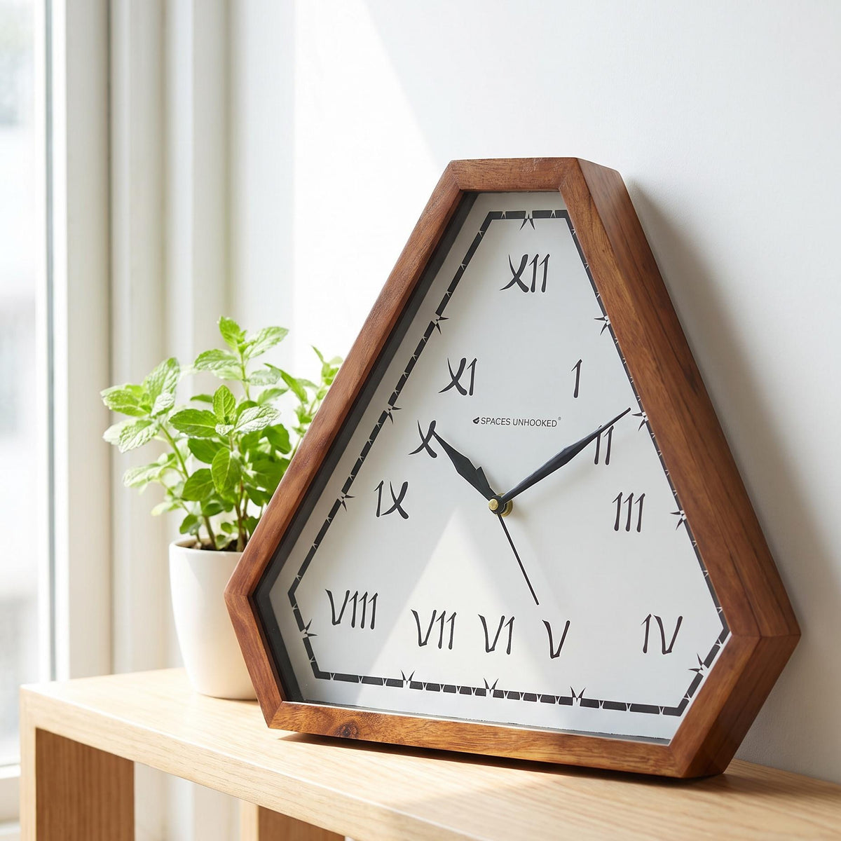 Spaces Unhooked triangular wooden wall clock with brush-style Roman numerals, front view