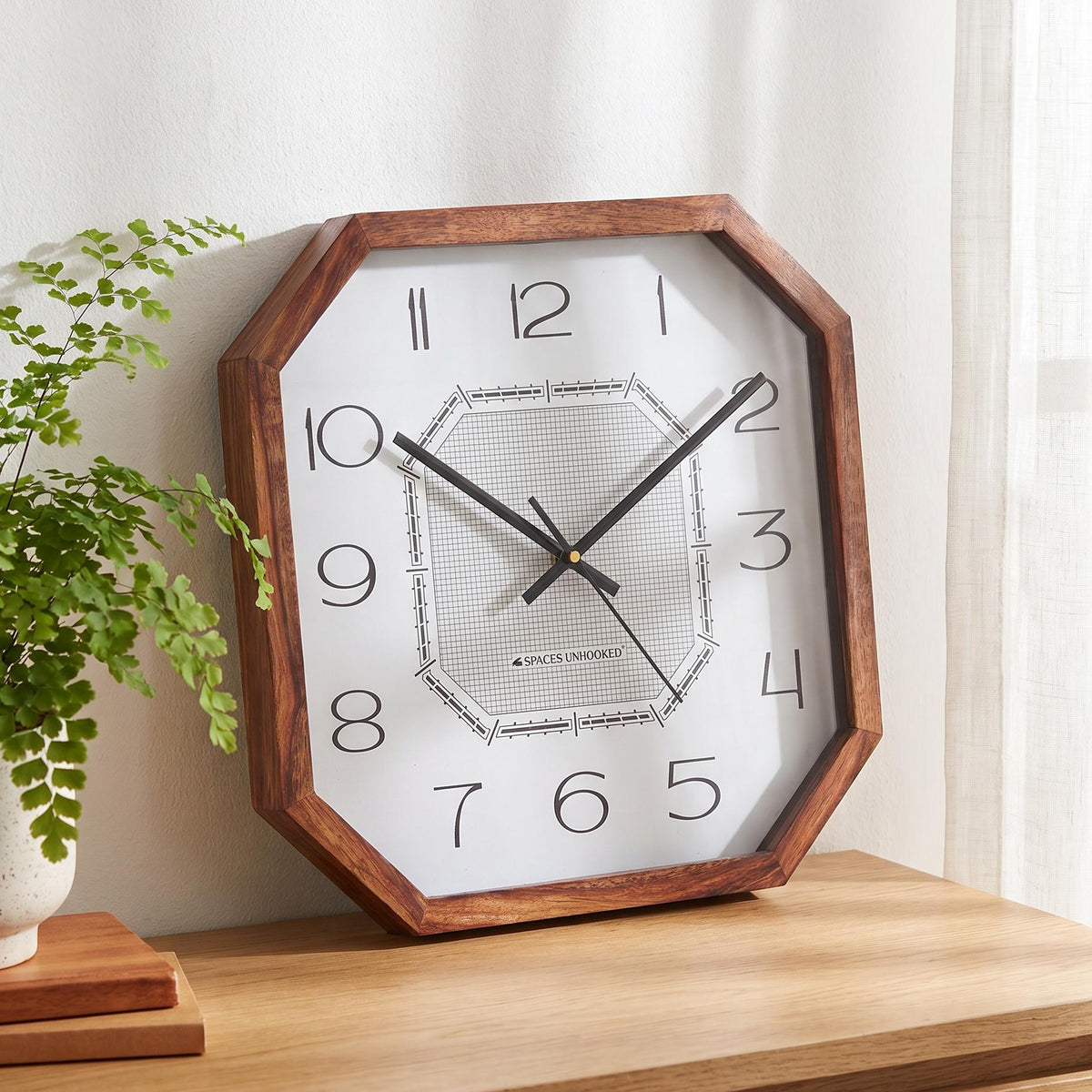 Art deco wooden wall clock above a writing desk in a creative studio or home office