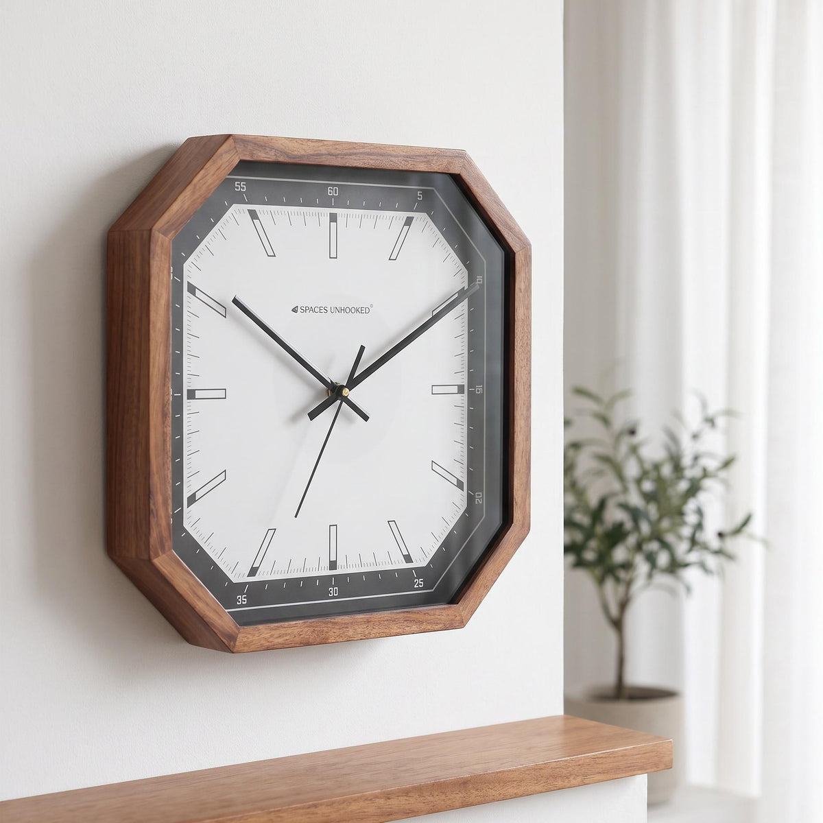 Black bezel octagonal wall clock in a bright studio apartment beside light wood furniture