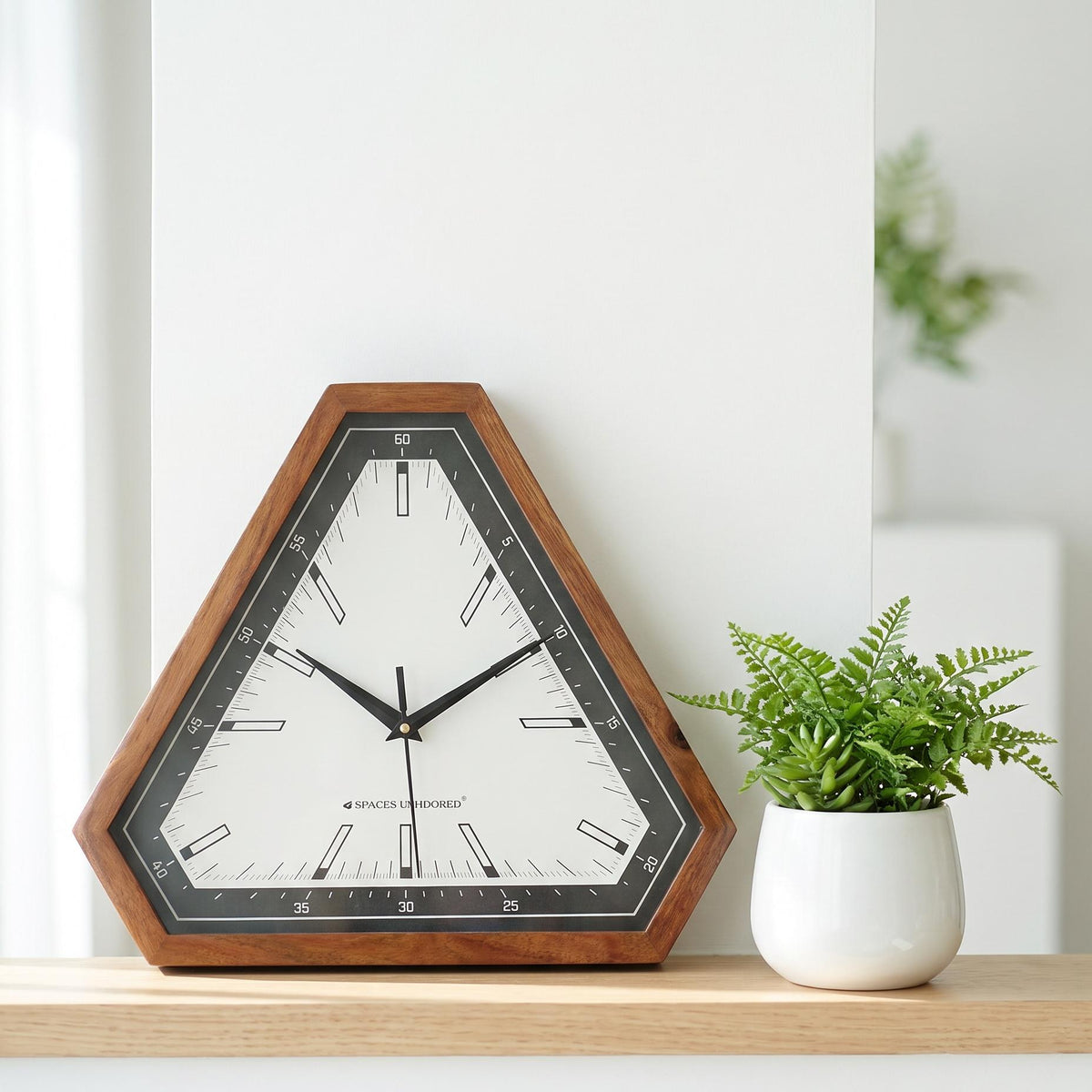 Spaces Unhooked triangular wooden wall clock with black bezel and white dial, front view