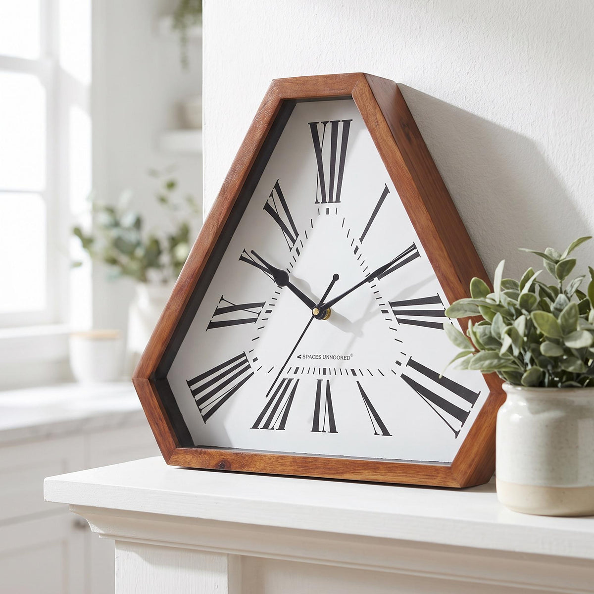 Spaces Unhooked bold Roman numeral triangular wooden wall clock with white dial, front view
