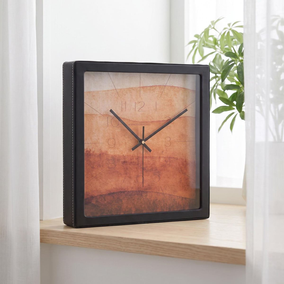 Terracotta watercolour wall clock on a bedroom wall beside a reading chair