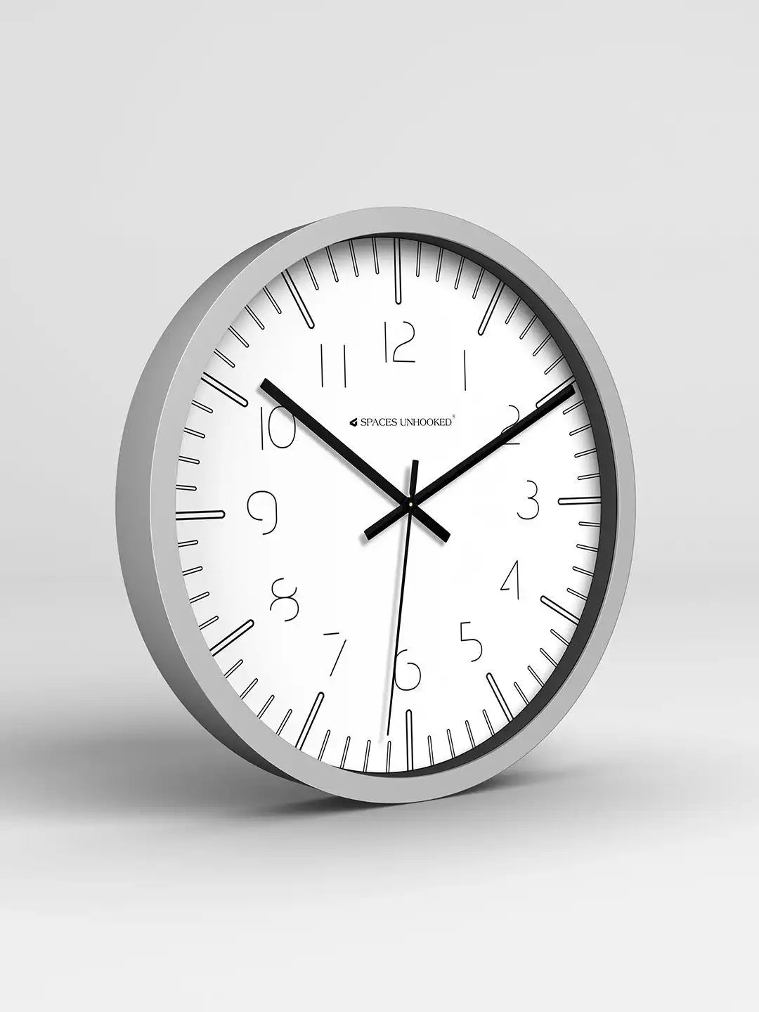 Wall clock with silver frame and white face on a light gray background