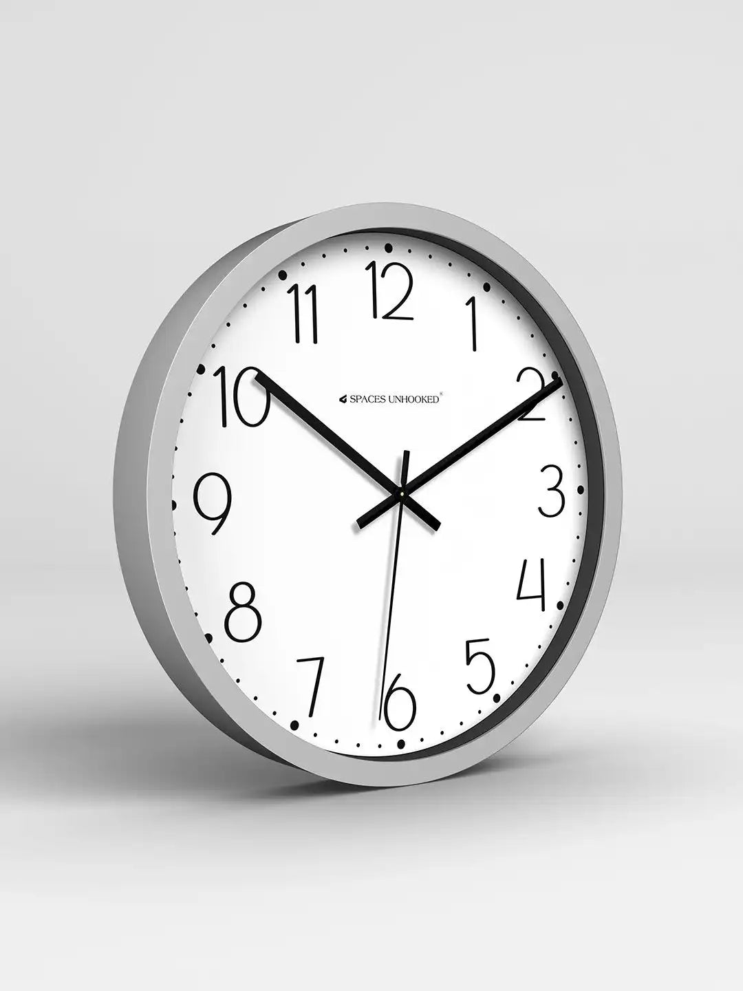 Wall clock with silver frame and white face on a light gray background