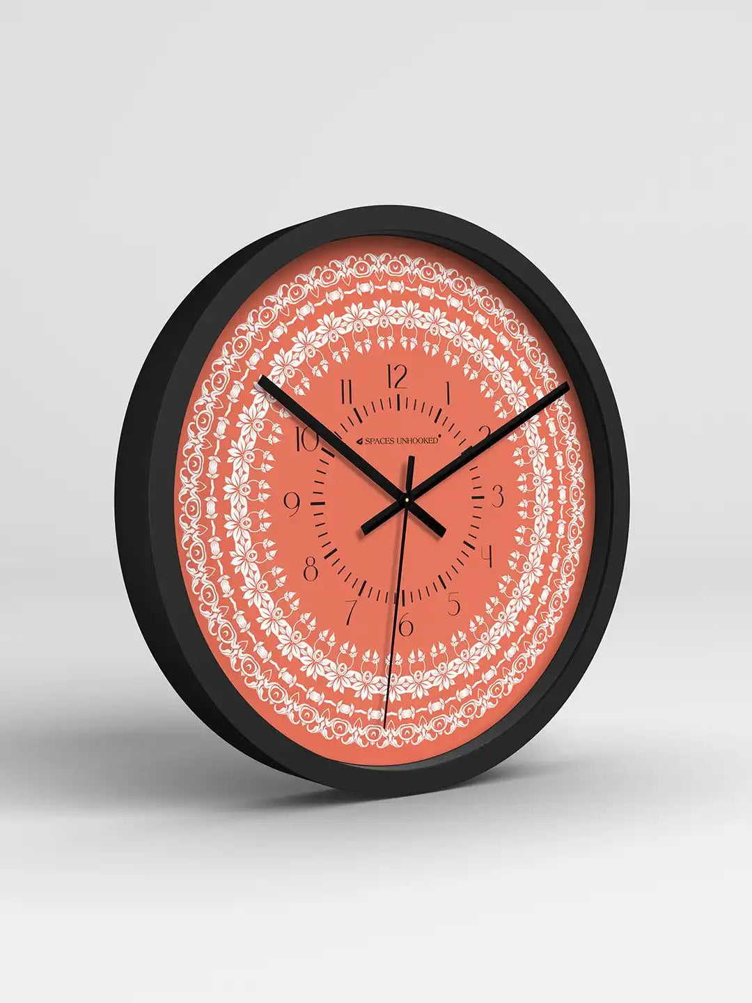 Wall clock with coral face and black frame on a light gray background
