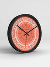 Wall clock with coral face and black frame on a light gray background