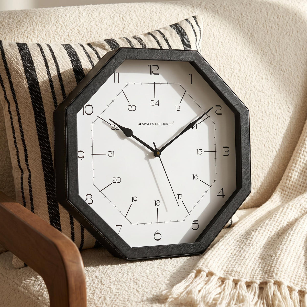 Octagonal black wall clock above a console table in a tidy hallway