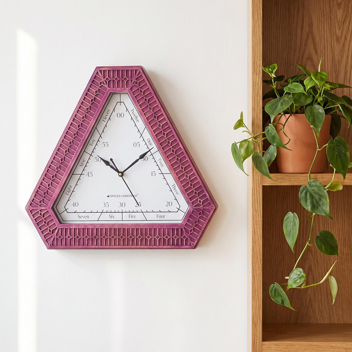 Close-up of the magenta carved geometric pattern on a triangular clock frame