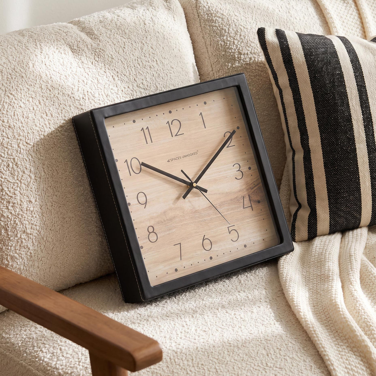 Black square frame and clear cover of a wood-look dotted dial wall clock, close-up view