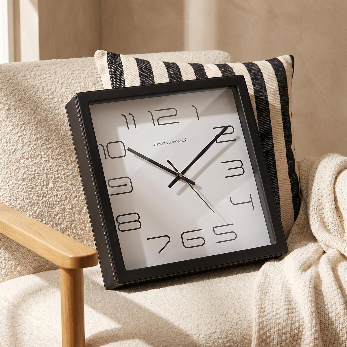 Spaces Unhooked logo above the brass-toned centre cap on a minimal clock dial
