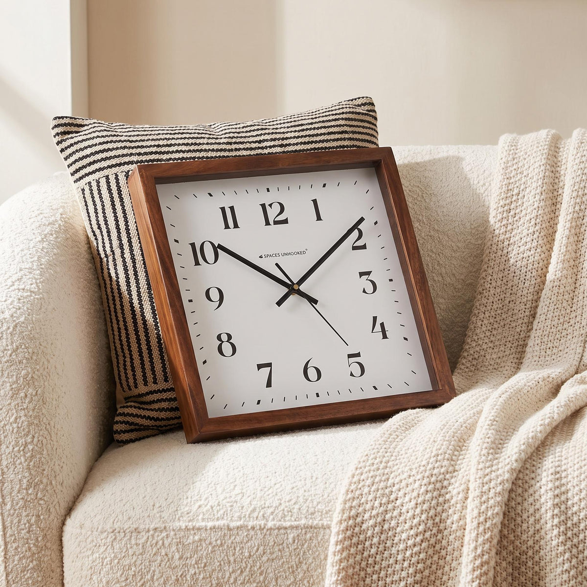 Spaces Unhooked logo above the brass-toned centre cap on a square wooden wall clock dial