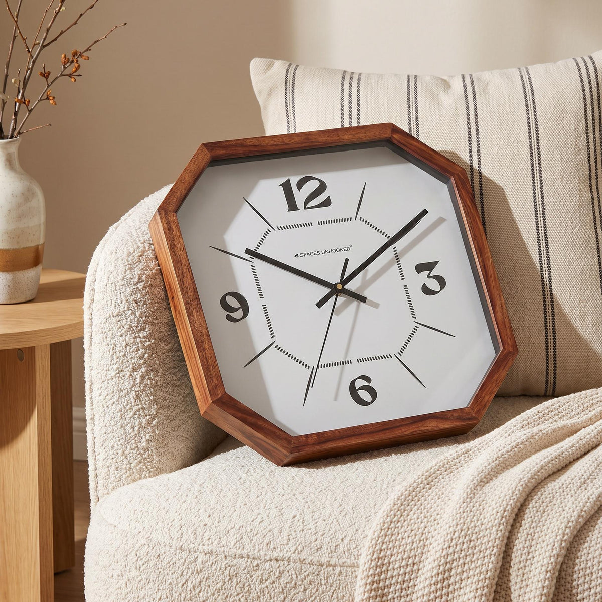 Slim black hands and fine second hand over the dotted centre of an octagonal wooden wall clock