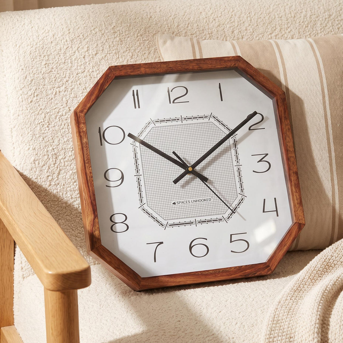 Slim black hands and thin second hand over the grid centre of an octagonal wooden wall clock