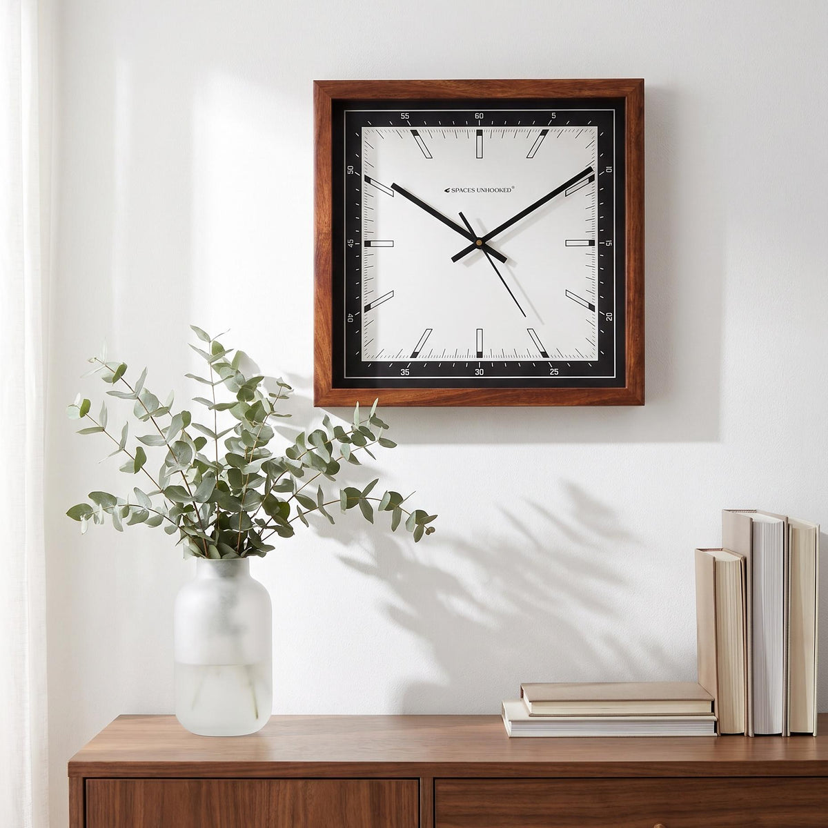 Long black hands and thin second hand across the bar markers of a square wooden wall clock